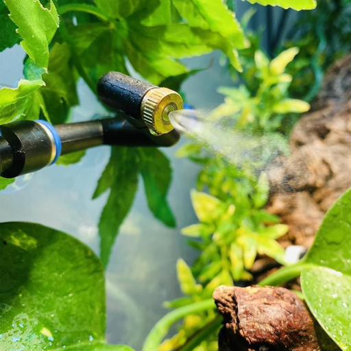 A close-up shows the HabiStat Rainmaker Pro by ReptiChip LLC spraying fine mist onto green plants, highlighting its automated system for precise humidity control in indoor or greenhouse settings.